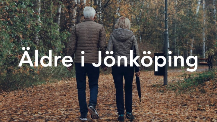 Äldre par som går hand i hand i lövskog.