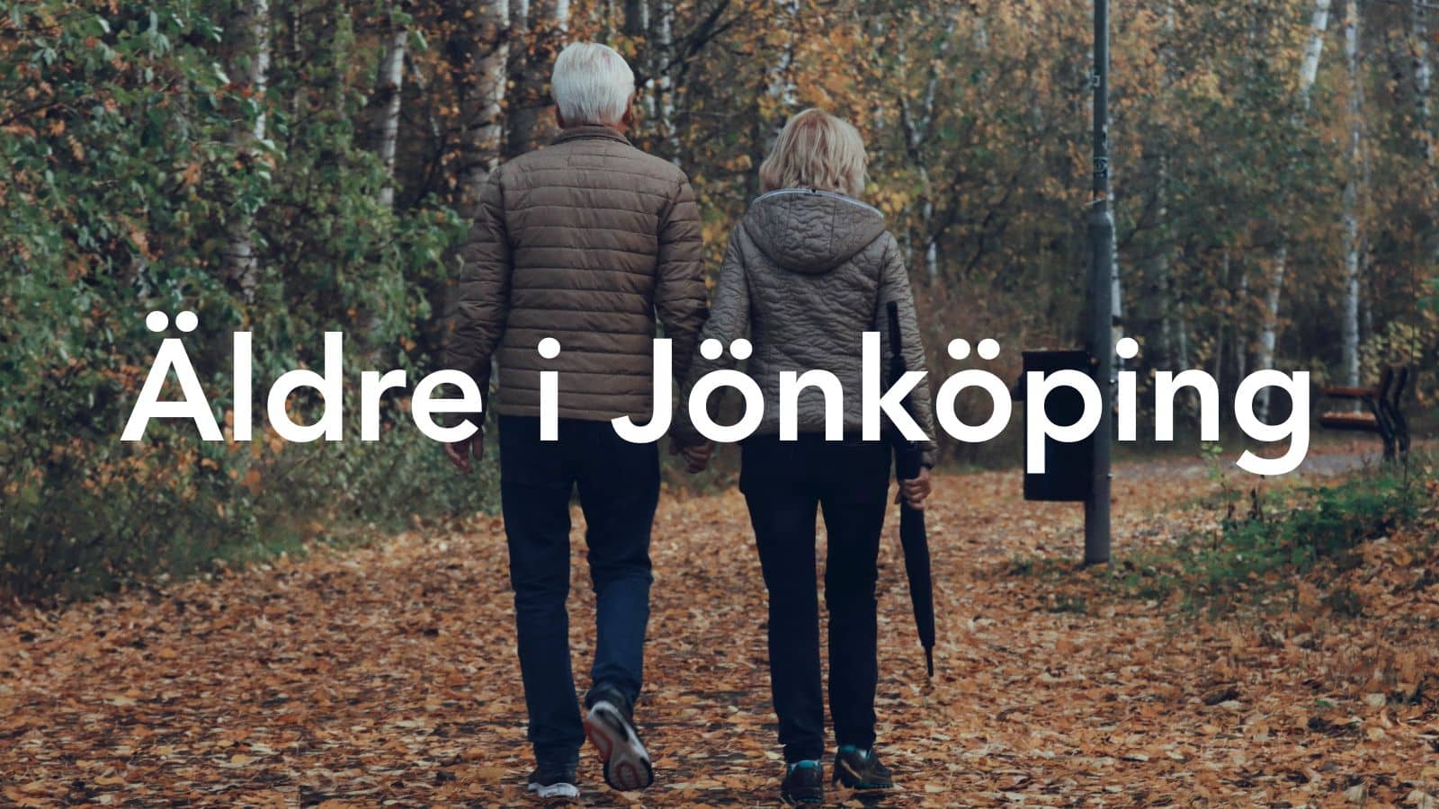 Äldre par som går hand i hand i lövskog.