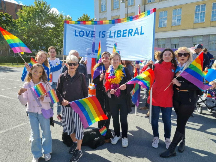 Färgglada människor som går i prideparad och representerar Liberalerna i Jönköping.