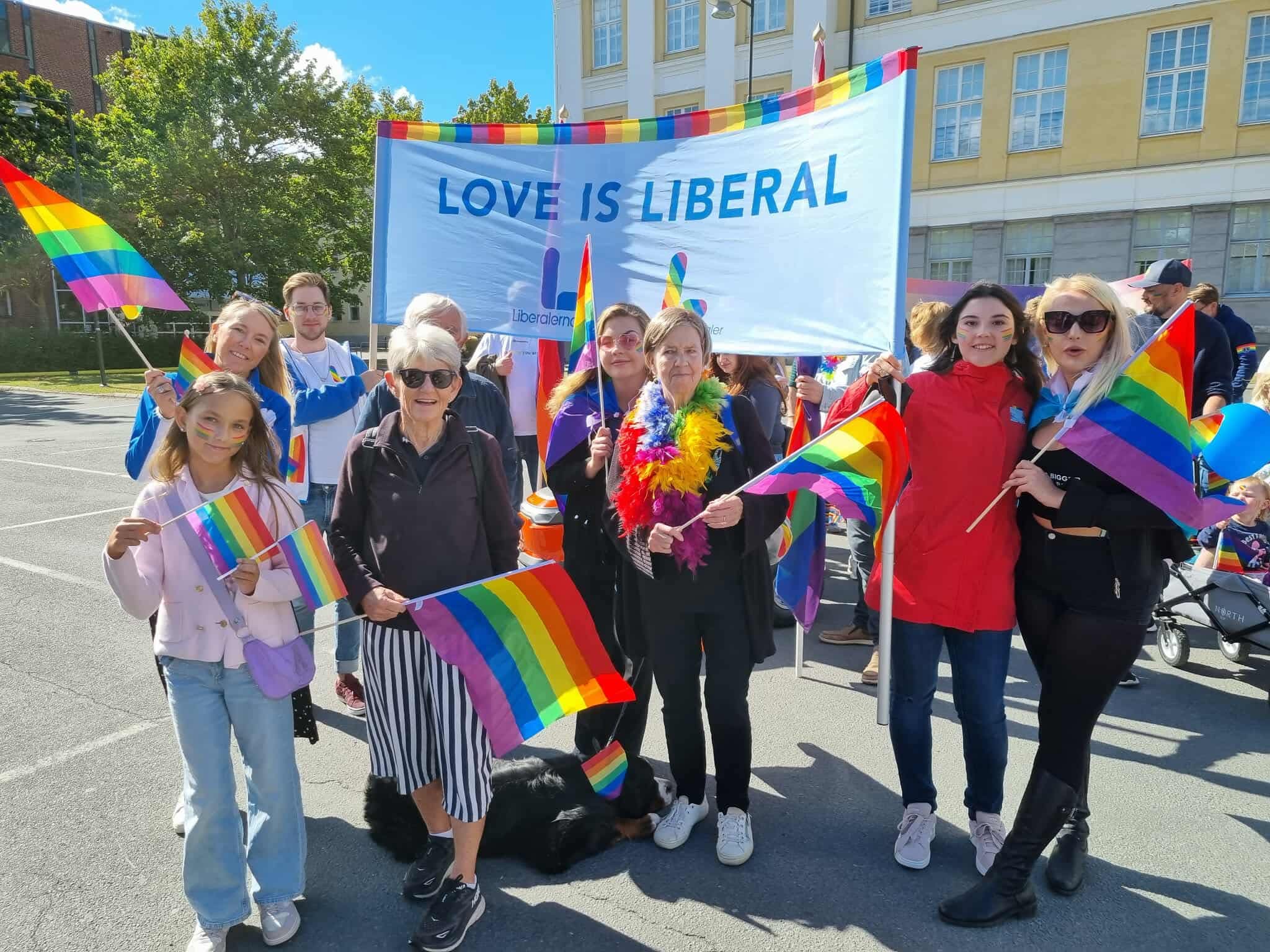 Färgglada människor som går i prideparad och representerar Liberalerna i Jönköping.